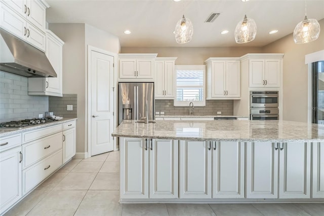 kitchen with white cabinetry, hanging light fixtures, appliances with stainless steel finishes, and a center island with sink