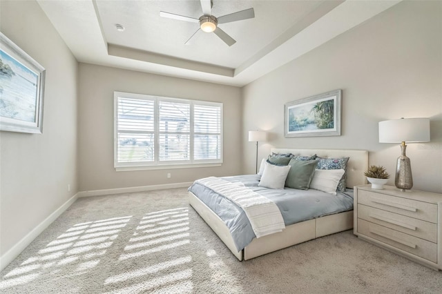 bedroom with ceiling fan, light carpet, and a raised ceiling