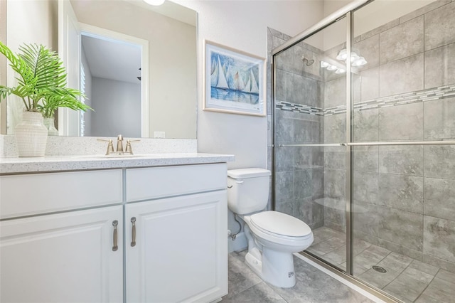 bathroom with a shower with shower door, vanity, and toilet