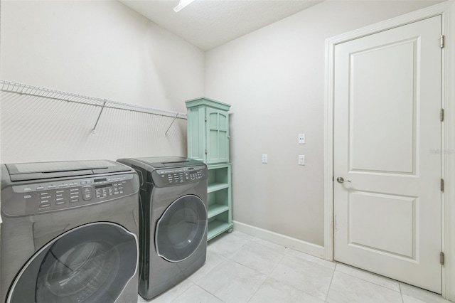 washroom featuring cabinets, separate washer and dryer, light tile patterned flooring, and a textured ceiling