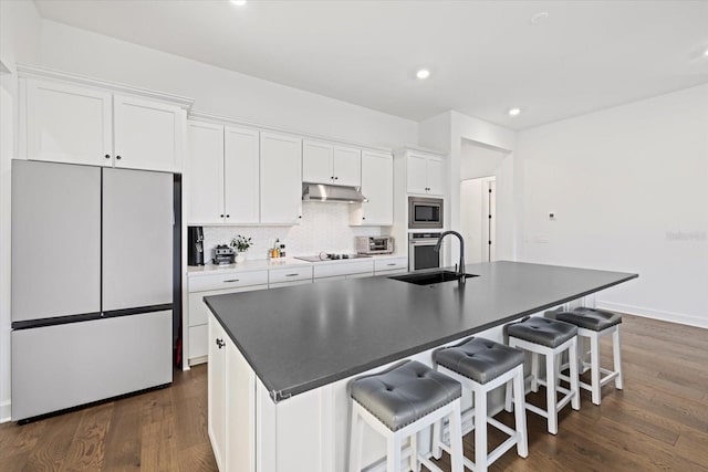 kitchen featuring white cabinetry, refrigerator, a center island with sink, and sink