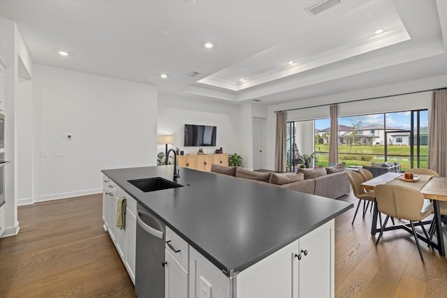 kitchen with a raised ceiling, sink, white cabinetry, an island with sink, and dark hardwood / wood-style flooring