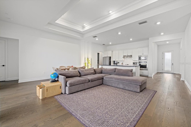 living room featuring hardwood / wood-style floors, a tray ceiling, and ornamental molding