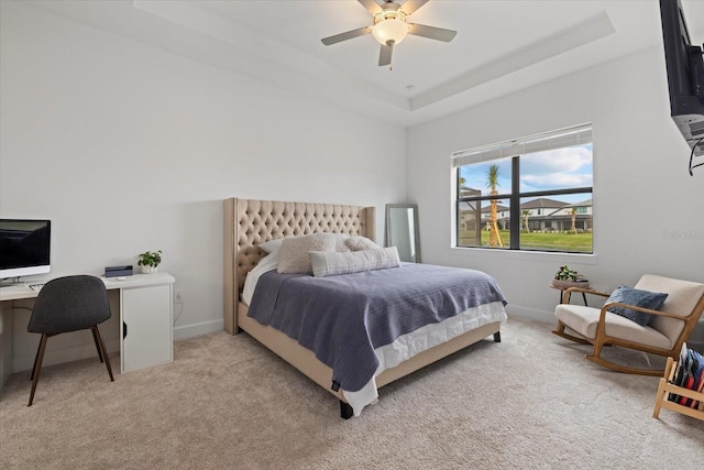 bedroom with a raised ceiling, ceiling fan, and light carpet