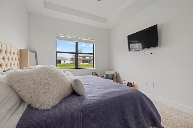 bedroom with carpet flooring and a tray ceiling