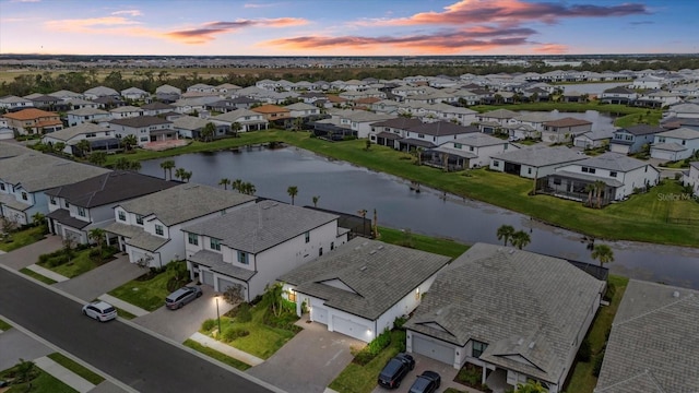 aerial view at dusk featuring a water view