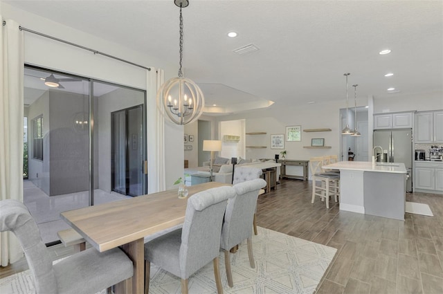 dining area featuring a raised ceiling, a textured ceiling, and a chandelier