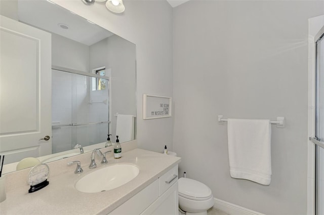 bathroom featuring vanity, a shower with shower door, and toilet