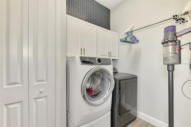 laundry area with washer and dryer, light wood-type flooring, and cabinets