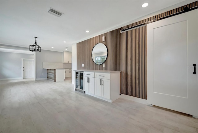 kitchen with decorative light fixtures, white cabinets, light wood-type flooring, and wine cooler