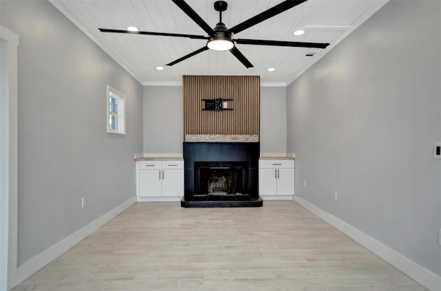 unfurnished living room featuring a fireplace, ornamental molding, ceiling fan, and light wood-type flooring