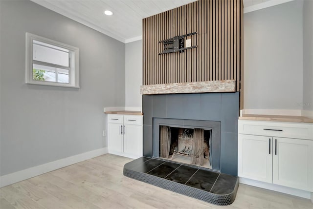 room details featuring ornamental molding, a tile fireplace, and wood-type flooring