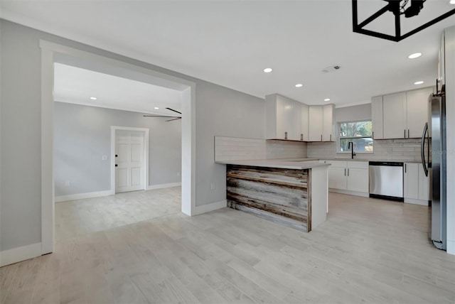 kitchen with light hardwood / wood-style flooring, stainless steel appliances, tasteful backsplash, white cabinets, and ceiling fan