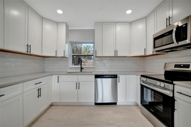 kitchen featuring sink, decorative backsplash, white cabinetry, and appliances with stainless steel finishes