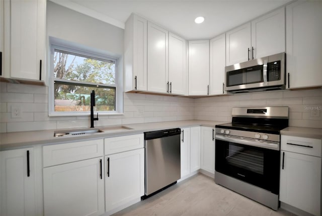 kitchen with stainless steel appliances, light wood-type flooring, white cabinets, and sink