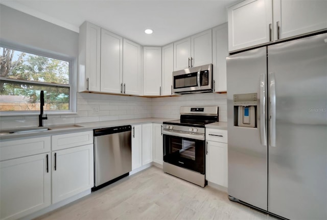 kitchen with stainless steel appliances, white cabinetry, decorative backsplash, and sink