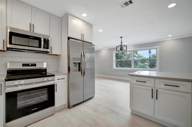 kitchen featuring stainless steel appliances, light wood-type flooring, hanging light fixtures, white cabinetry, and tasteful backsplash