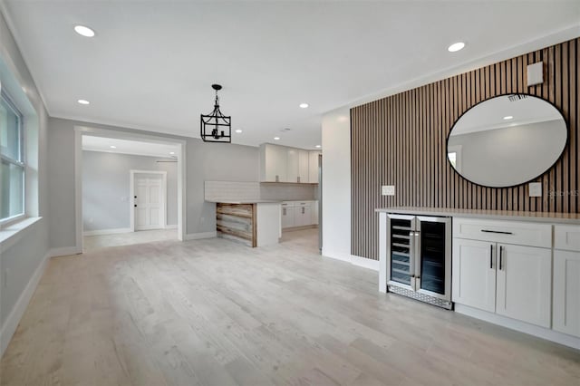 bar with white cabinets, hanging light fixtures, light hardwood / wood-style floors, and wine cooler