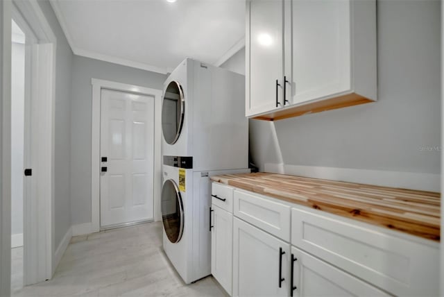 laundry room featuring light wood-type flooring, cabinets, ornamental molding, and stacked washer and clothes dryer