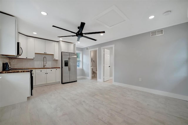 kitchen with stainless steel appliances, ceiling fan, light hardwood / wood-style flooring, white cabinetry, and tasteful backsplash