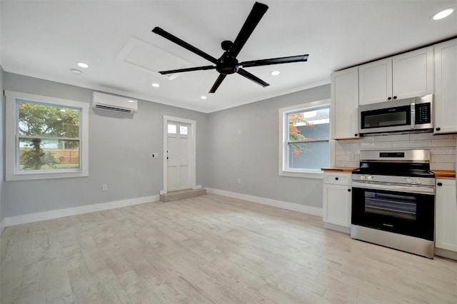 kitchen featuring a wall unit AC, appliances with stainless steel finishes, and white cabinetry