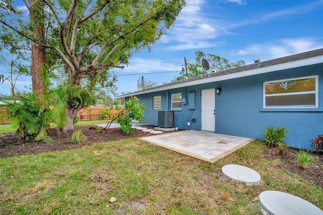 rear view of property with a patio, a lawn, and central AC