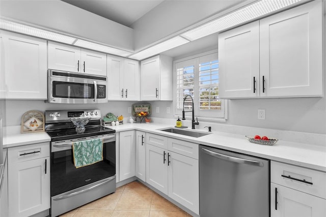 kitchen with white cabinetry, stainless steel appliances, sink, and light tile patterned floors