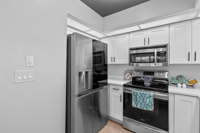 kitchen featuring light tile patterned floors, stainless steel appliances, and white cabinets