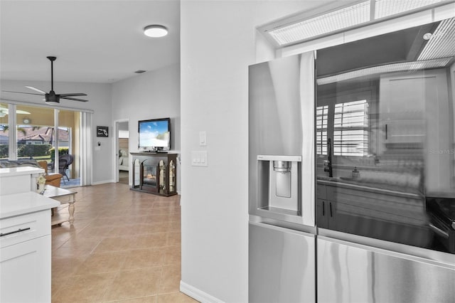 kitchen featuring light tile patterned floors, vaulted ceiling, white cabinets, and ceiling fan