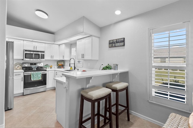 kitchen featuring stainless steel appliances, white cabinets, and kitchen peninsula