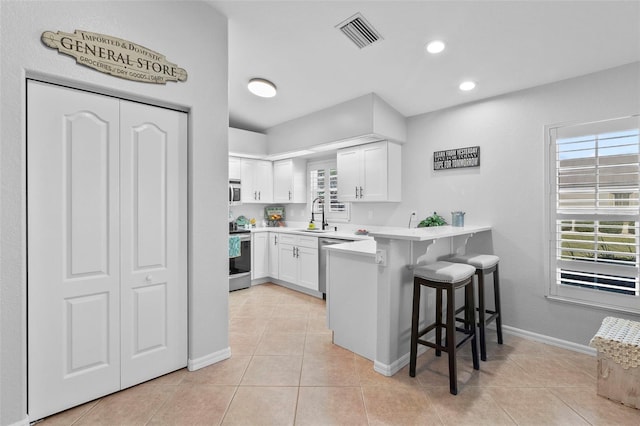 kitchen with sink, stainless steel appliances, white cabinets, a kitchen bar, and kitchen peninsula