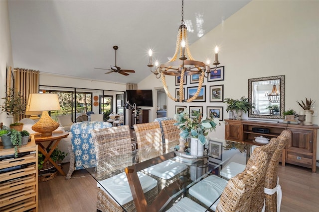 dining area featuring dark wood-type flooring, high vaulted ceiling, and ceiling fan with notable chandelier