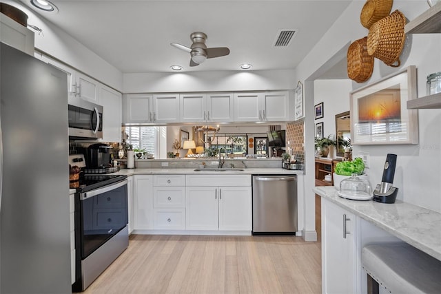 kitchen featuring stainless steel appliances, sink, light hardwood / wood-style flooring, and white cabinets