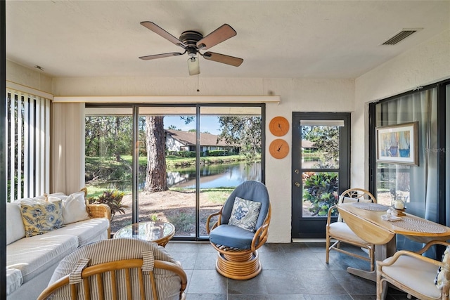 sunroom / solarium with ceiling fan and a water view