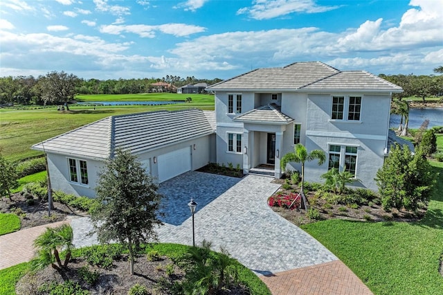 view of front facade with a front yard, a garage, and a water view