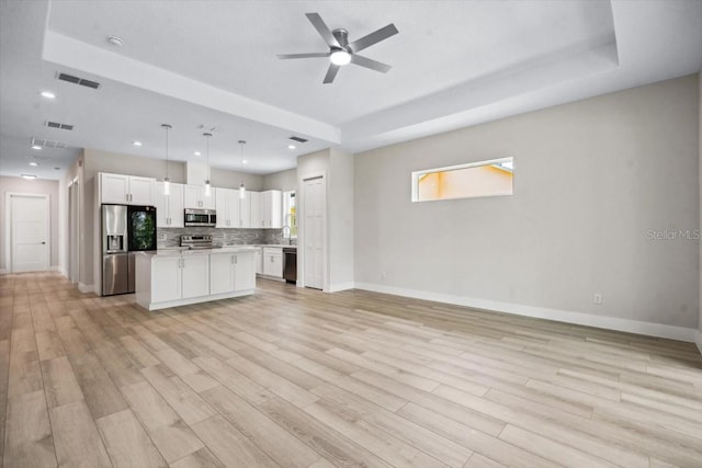 kitchen featuring pendant lighting, a center island, white cabinets, decorative backsplash, and appliances with stainless steel finishes