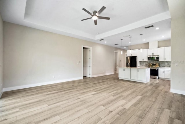 unfurnished living room featuring light wood-type flooring, a raised ceiling, and ceiling fan