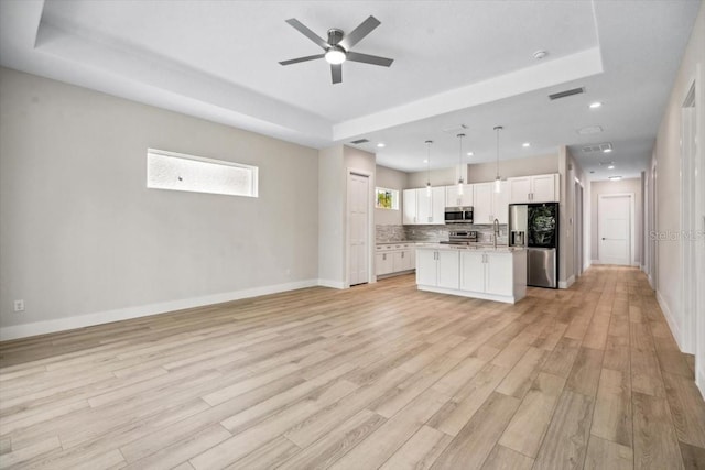 kitchen with white cabinetry, a center island, pendant lighting, appliances with stainless steel finishes, and light wood-type flooring