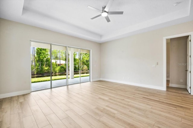 spare room featuring ceiling fan, a raised ceiling, and light wood-type flooring