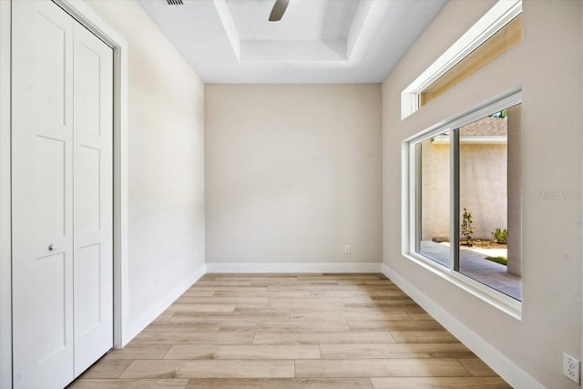 interior space featuring light hardwood / wood-style floors, a raised ceiling, a wealth of natural light, and ceiling fan