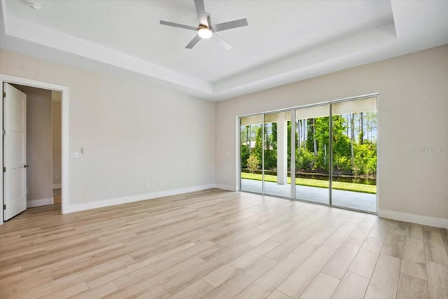 unfurnished room featuring light wood-type flooring, a raised ceiling, and ceiling fan