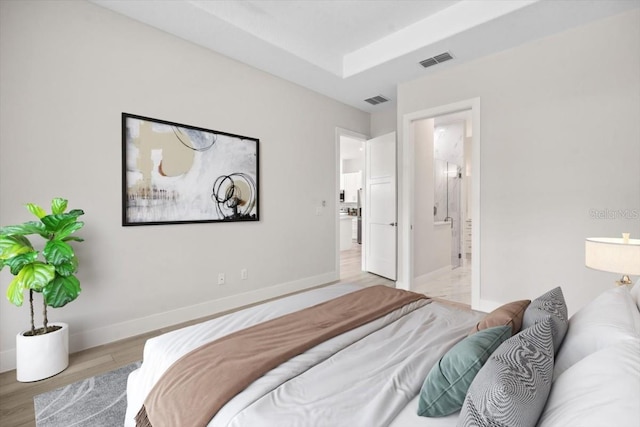 bedroom with ensuite bathroom and light hardwood / wood-style floors