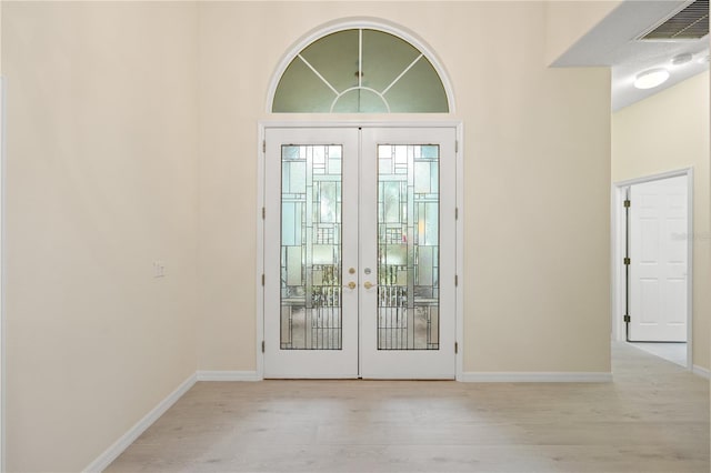 entryway featuring light wood finished floors, visible vents, french doors, and baseboards