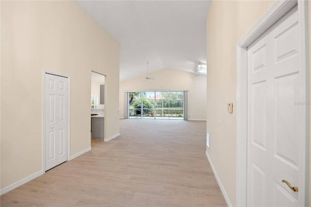 corridor with vaulted ceiling, light wood-style floors, and baseboards