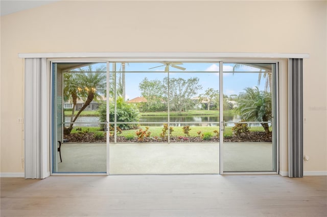 doorway to outside featuring vaulted ceiling, plenty of natural light, wood finished floors, and a water view