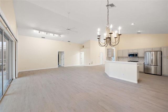 kitchen featuring light wood-type flooring, high vaulted ceiling, ceiling fan with notable chandelier, tasteful backsplash, and appliances with stainless steel finishes