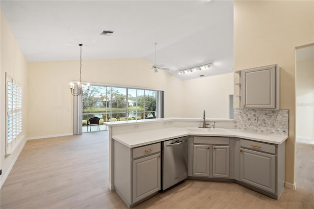 kitchen featuring light wood finished floors, a peninsula, gray cabinets, a sink, and stainless steel dishwasher