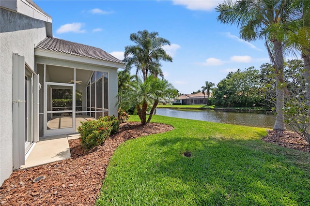 view of yard with a sunroom and a water view