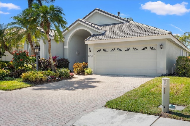 view of front of home featuring stucco siding, decorative driveway, an attached garage, and a tiled roof