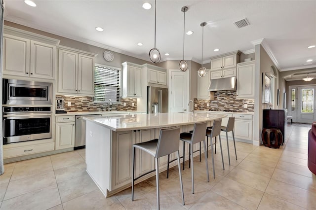 kitchen featuring hanging light fixtures, backsplash, a center island with sink, stainless steel appliances, and light tile patterned flooring